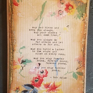 May include: A vintage-style image with a floral background and a poem by Bob Dylan. The poem reads: "May God bless and keep you always. May your wishes all come true. May you always do for others and let others do for you. May you build a ladder to the stars and climb on every rung. May you stay forever young, forever young, forever young. May you stay forever young. - Bob Dylan"