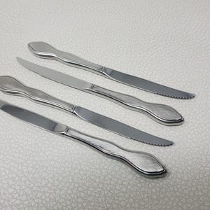 May include: A white-painted wooden 'Welcome' sign with a distressed finish. The sign features a floral design in pink and green. The text is in a whimsical font. Suitable for indoor or outdoor use. The sign is handmade.