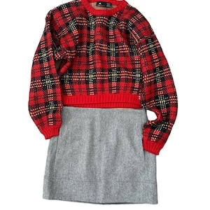 May include: A red and black plaid cropped sweater with a gray mini skirt. The sweater has a yellow and white pattern.