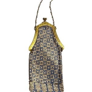 May include: An antique metal mesh purse with a gold-toned frame and chain handle. The purse features a pattern of blue and silver squares, with a scalloped bottom edge. The clasp is heart-shaped.