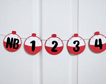 May include: A festive banner featuring red and white circular ornaments strung on a white string. Each ornament displays a black number or letters, ranging from "NB" to "4". The banner is set against a white background.