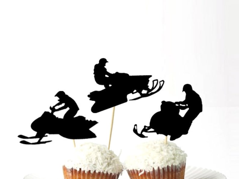 May include: Three black silhouette cupcake toppers featuring snowmobilers. Each topper depicts a person riding a snowmobile with a black silhouette design.