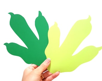 Op de afbeelding: Twee dinosaurusvoetafdrukken uit papier geknipt. Eén voetafdruk is groen en de andere is geelgroen.