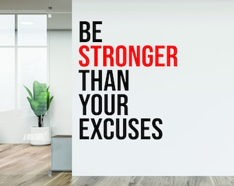 May include: A white wall with the motivational quote "BE STRONGER THAN YOUR EXCUSES" written in black and red letters. The wall is in an office setting with glass walls and a wooden floor.