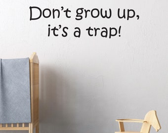 May include: A white wall with black text that reads "Don't grow up, it's a trap!"  A wooden crib with a blue blanket is on the left side of the image. A wooden rocking horse and a blue toy car are on the floor in front of the wall.