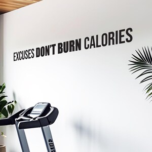 May include: A white wall with the phrase "EXCUSES DON'T BURN CALORIES" in large black letters. A treadmill is in the foreground, and a palm frond is visible on the right side of the image.