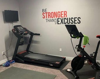May include: A home gym with a black treadmill and a black stationary bike. The wall has a motivational quote in red and black that says "Be Stronger Than Your Excuses".
