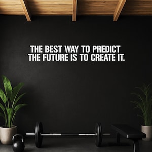 May include: A motivational quote in white lettering on a black wall: "THE BEST WAY TO PREDICT THE FUTURE IS TO CREATE IT." The image includes gym equipment: a barbell, kettlebell, and weight bench, with potted plants on either side.