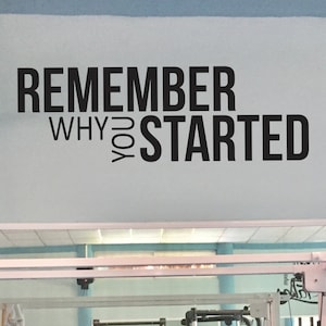 May include: Black and white motivational quote on a light blue wall. The quote reads "Remember why you started."