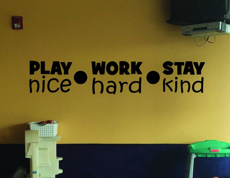 May include: A yellow wall with black lettering that reads "Play nice, work hard, stay kind".