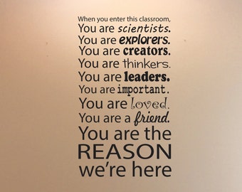 May include: A wall decal with black text on a beige background. The text reads: "When you enter this classroom, You are scientists. You are explorers. You are creators. You are leaders. You are the REASON we're here."