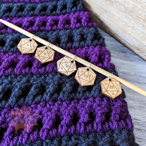 Könnte beinhalten: Holzstiche mit Zahlen 1, 5, 7, 8, 10/12, 13, 15, 17, 18, 20 und 24 auf einer Holzstricknadel. Die Stiche befinden sich auf einer gestrickten Decke mit violetten und schwarzen Streifen.
