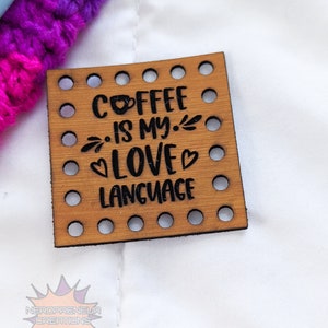 May include: A wooden square sign with holes around the edges. The sign has the text "Coffee is my love language" with a coffee cup icon and a heart.
