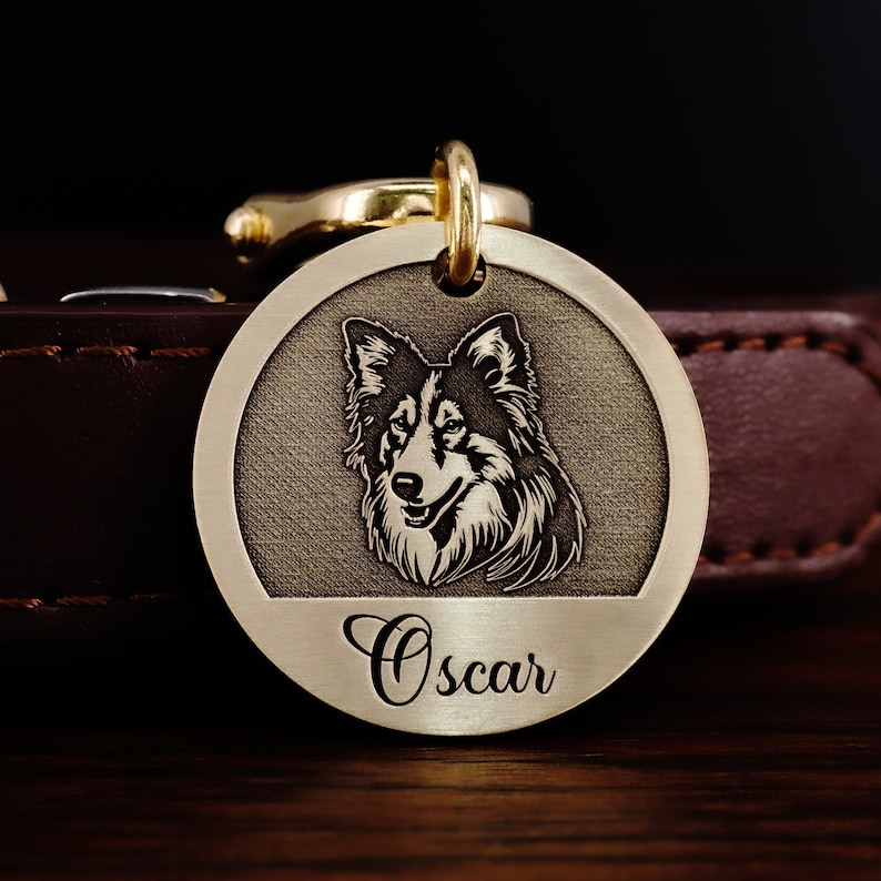 May include: A gold-colored dog tag with a black and white image of a dog's head and the name "Oscar" engraved on the bottom.