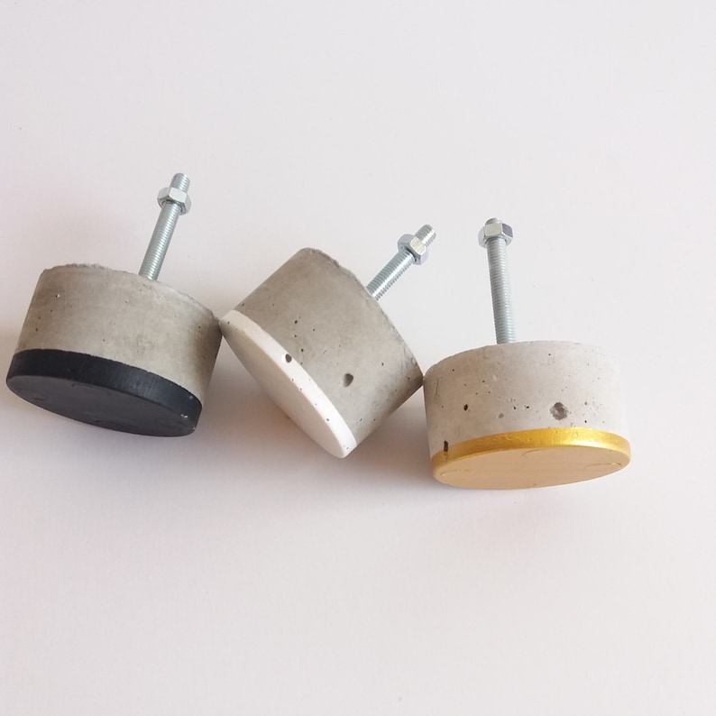 Peut inclure: Trois poign&eacute;es de tiroir en b&eacute;ton avec quincaillerie m&eacute;tallique. Les poign&eacute;es ont un accent noir, blanc et or.