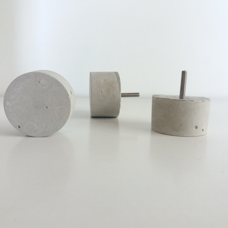 May include: Three concrete knobs with a silver screw. The knobs are round and have a rough texture.