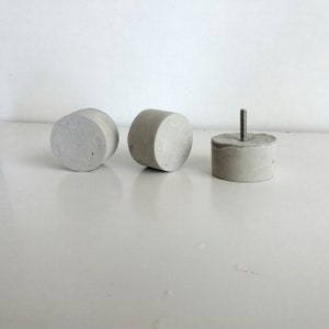 May include: Three grey concrete knobs, one with a metal screw protruding from the top.