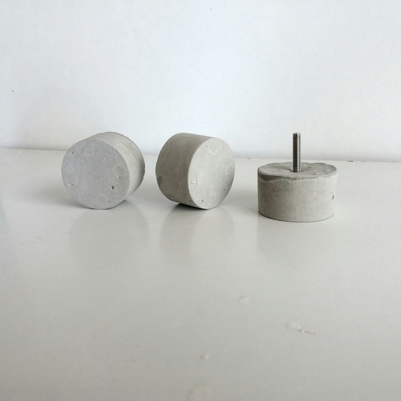May include: Three grey concrete knobs, one with a metal screw protruding from the top.