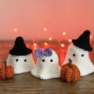 May include: Handmade crochet Halloween decorations. Three white ghost figures with black hats and purple bow. Two small orange pumpkins are also included. The text "Crochet 'N Things by Rachael" is visible.