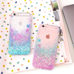 May include: Two clear phone cases with glitter and star accents. One case has blue, purple, and silver glitter, while the other has pink, purple, and silver glitter. Both cases have an Apple logo.