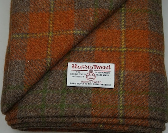 Może przedstawiać: Tkanina tweedowa w kolorze brązowym i pomarańczowym z zielono-żółtym wzorem w kratę. Tkanina ma etykietę z napisem "Harris Tweed" i logo Harris Tweed Authority. Etykieta zawiera również napis "Certification Trade Mark" i "Hand Woven in the Outer Hebrides".