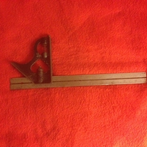 May include: A metal protractor with a sliding ruler. The protractor has a black finish and the ruler is silver.