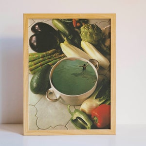 May include: A white ceramic bowl filled with green liquid, surrounded by various vegetables, including asparagus, aubergine, avocado, and a spring onion. The bowl is on a tiled surface.