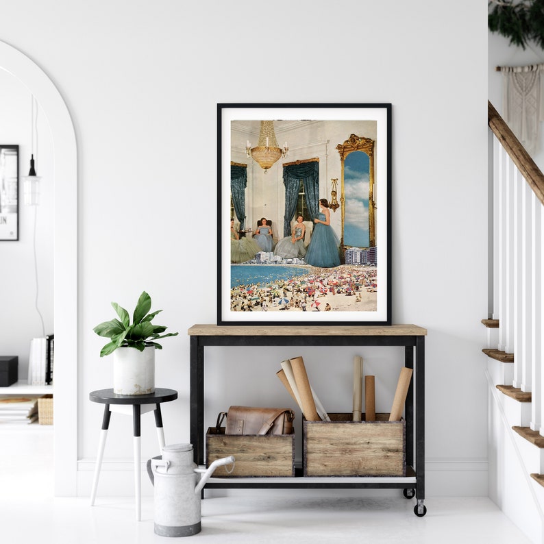 May include: A framed collage art print featuring a surreal scene of women in blue dresses standing in a room with a large mirror reflecting a beach scene with people.