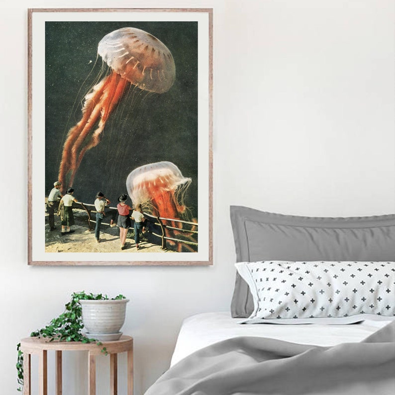 May include: A framed print of a surrealist collage featuring two large jellyfish floating above a group of people standing on a boardwalk. The jellyfish are pink and white with long tentacles. The people are wearing vintage clothing and looking up at the jellyfish.