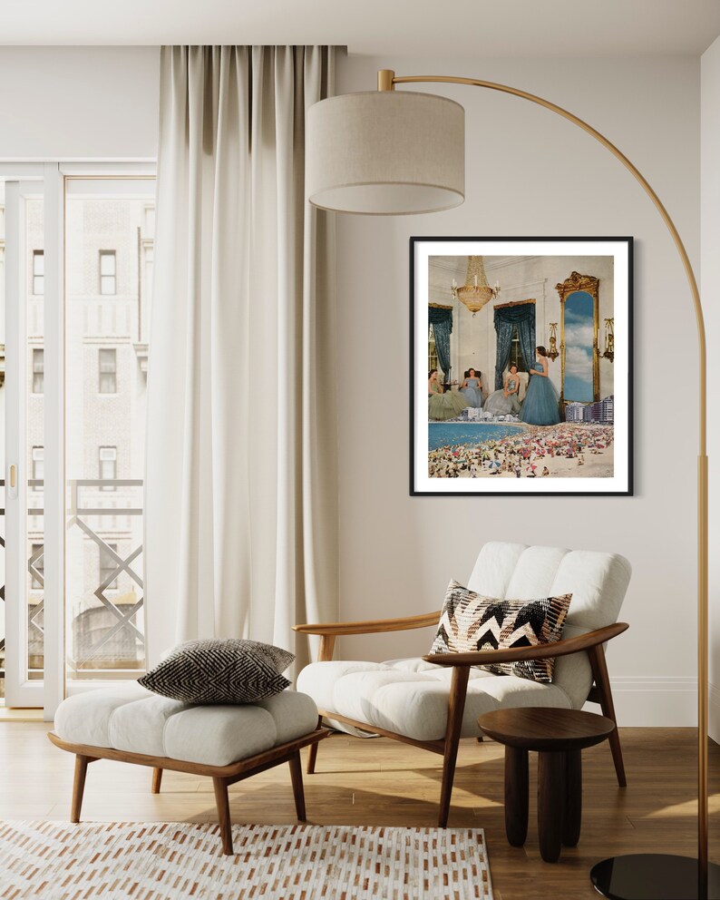 May include: A framed print of a surrealist collage featuring women in blue dresses standing on a beach with a miniature city in the background.