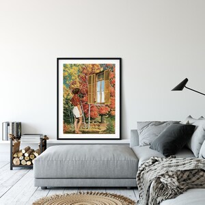 May include: A framed art print depicting a person gazing out of a window with open shutters, set against a backdrop of autumnal trees. The artwork showcases a vivid scene with a blue sky and deer. The print is displayed in a living room.