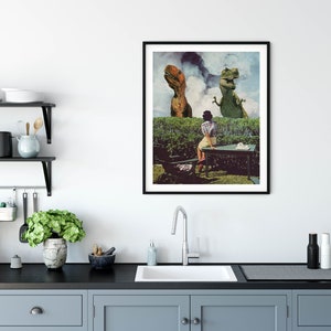 May include: A framed collage print featuring a woman sitting at a table in a garden setting with two dinosaurs in the background. The dinosaurs are green and brown and appear to be looking at the woman. The print has a vintage aesthetic.