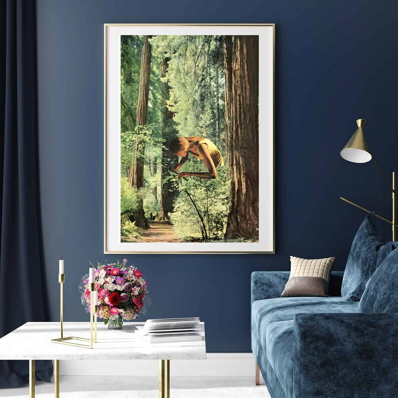 May include: A framed art print featuring a surreal collage of a person suspended in a forest. The artwork has a vintage aesthetic with a color palette of greens, browns, and yellows. The print is displayed in a gold frame, adding a touch of elegance to the wall decor.