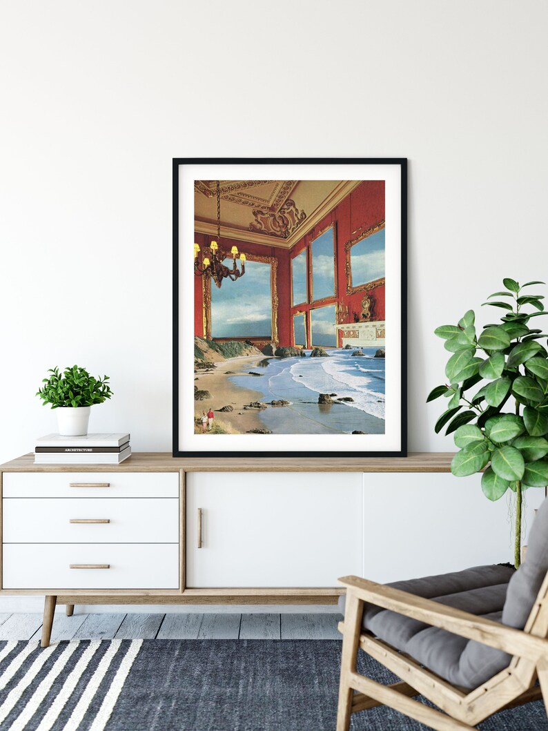 May include: A framed print of a surrealist artwork depicting a red room with multiple windows that open to a beach scene with crashing waves. The room has a chandelier and a fireplace.