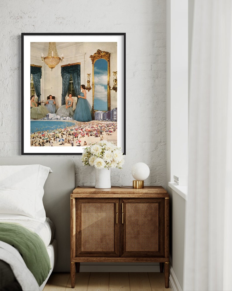 May include: A framed print of a surrealist collage featuring three women in blue dresses standing in a room with a large mirror that reflects a beach scene with people and umbrellas.