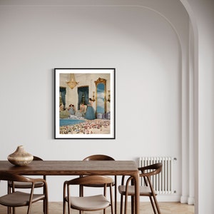 May include: A framed collage artwork depicting a room with a chandelier and a mirror reflecting a beach scene with people. The women in the room are wearing blue dresses.