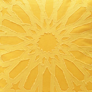 Pu&ograve; includere: Una federa quadrata giallo brillante con un motivo centrale a stella creato con ritagli di tessuto sfilacciati dai bordi grezzi. Il design &egrave; composto da forme geometriche che si irradiano dal centro, mostrando un aspetto stratificato e testurizzato.