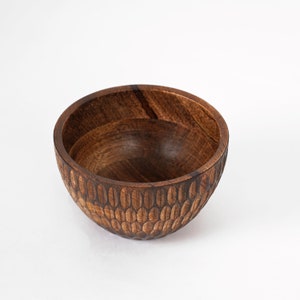 May include: A dark brown wooden bowl with a textured, patterned exterior. The bowl is empty and has a rounded shape.