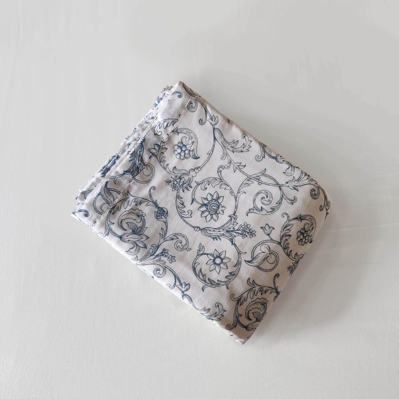 May include: A folded piece of fabric with a white background and a blue floral pattern.