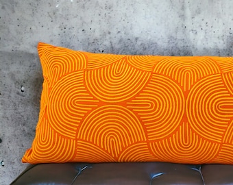 May include: Orange lumbar pillow with a geometric pattern of yellow arches.