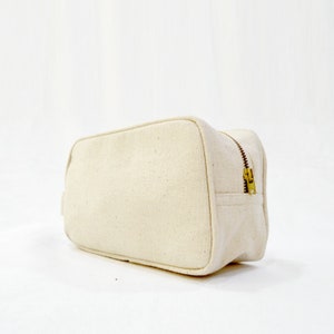 Toiletry bag, off white, zip closure.