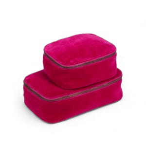 May include: Two pink velvet zippered pouches stacked on top of each other. The pouches are a bright, vibrant pink.