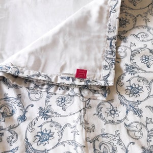 May include: White bedding with a blue and white floral pattern. The bedding has a white label with the text "VILLA" in red.