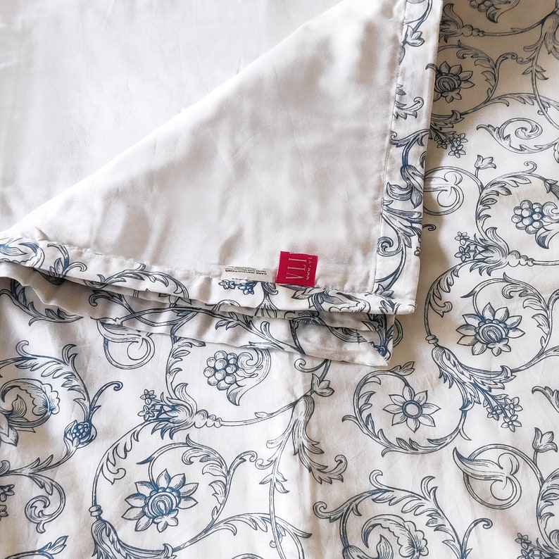 May include: White bedding with a blue and white floral pattern. The bedding has a white label with the text "VILLA" in red.