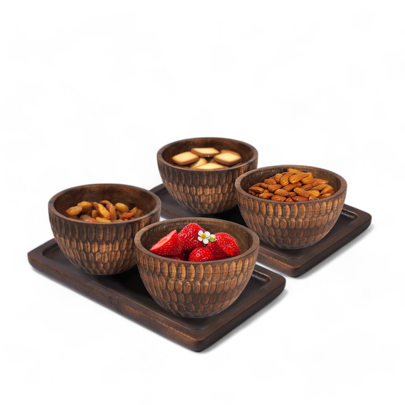 May include: Four wooden bowls with a textured surface, filled with different snacks, are arranged on a wooden tray. The bowls contain almonds, dried fruit, strawberries, and cookies.