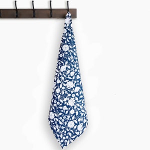 May include: A blue kitchen towel with a white floral pattern. The towel is hanging on a wooden rack with metal hooks.