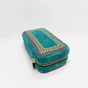 May include: Teal blue velvet jewellery box with a colourful embroidered border and a gold zipper.