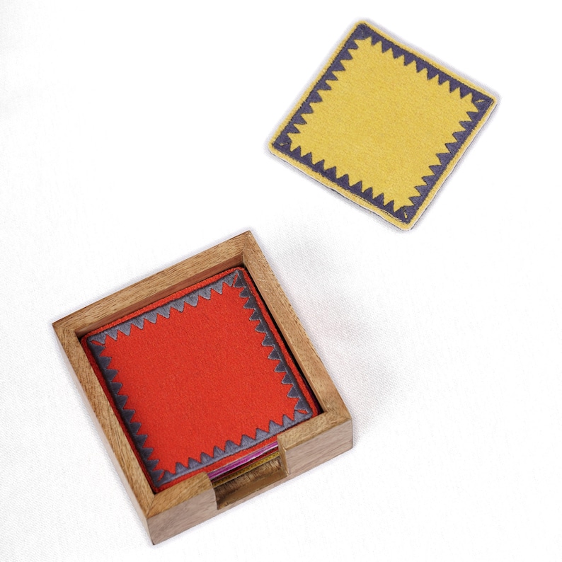 Peut inclure: Un ensemble de dessous-de-verre color&eacute;s avec une bordure d&eacute;corative cousue. Les dessous-de-verre sont dans un support en bois. Les dessous-de-verre sont rouge, jaune et violet.