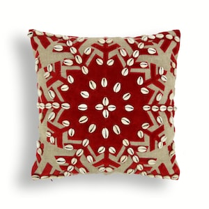 May include: Square decorative pillow with a red velvet geometric design and beige linen background. The design is embellished with white seashells. The pillow is a square shape.