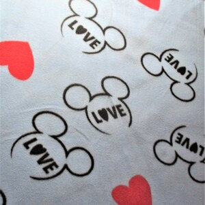 May include: A light blue fabric with a repeating pattern of black Mickey Mouse ears with the word "LOVE" inside each ear and red hearts.
